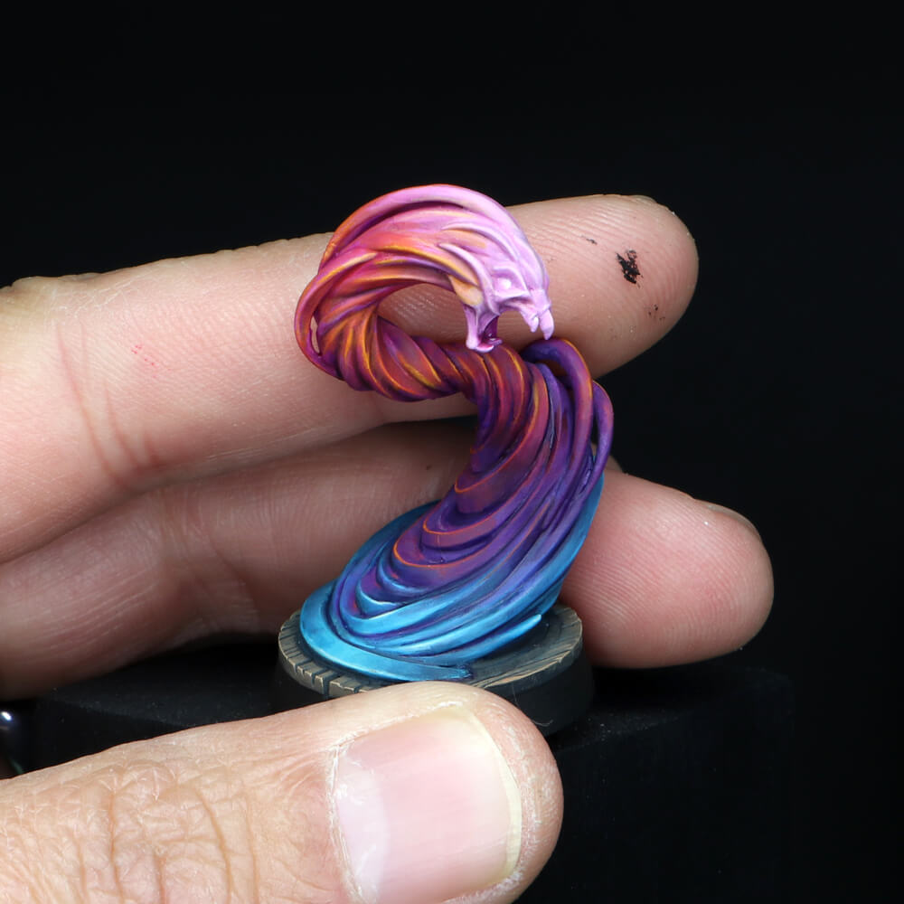 A hand holding a vibrantly painted D&D miniature of a magical vortex with a blue-to-pink color gradient
