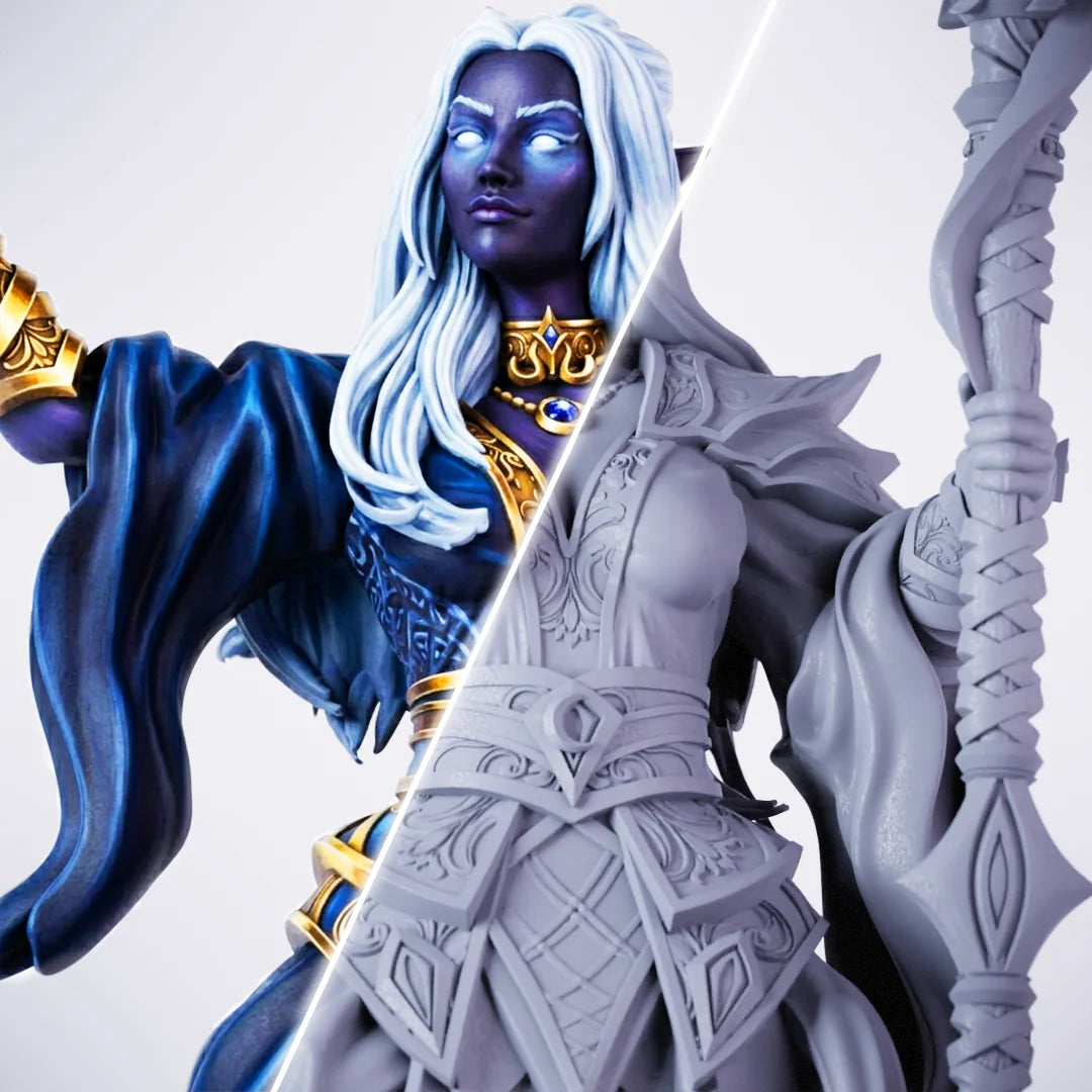 Kadna Chosen – painted/unpainted split view of a female dark-elf or drow miniature with deep blue skin, long white hair, blue-and-gold arcane robes, and a tall staff